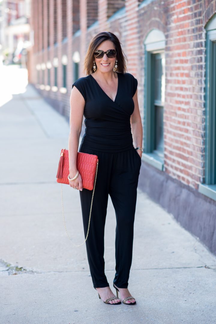 How to Wear a Jumpsuit: Pair a black jumpsuit with high heeled leopard sandals, and add a bright clutch.
