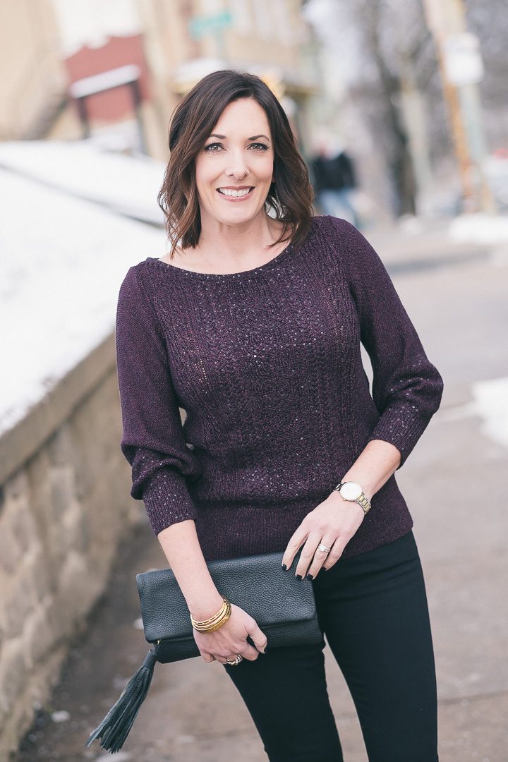 New Year's Eve party outfit with plum sequined pullover and black jeans