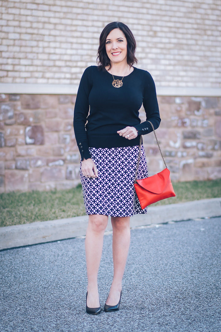 Jo-Lynne Shane wearing an early spring work wear look with LE LIS Maura Zip Pocket Detail Skirt from Stitch Fix with black Sam Edelman Hazel pumps and a red handbag.