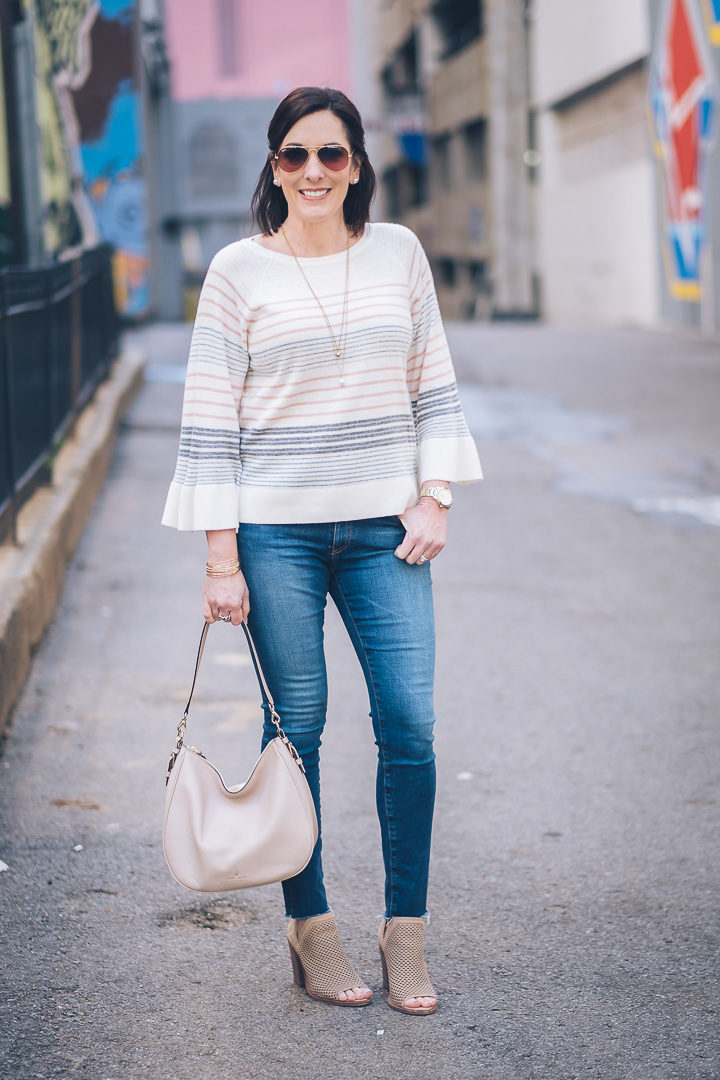A dressed-up casual spring outfit featuring LOFT mixed stripe bell sleeve sweater with AG raw hem legging ankle jeans and Vince Camuto perforated peep toe booties. Also wearing kate spade new york mylie hobo.