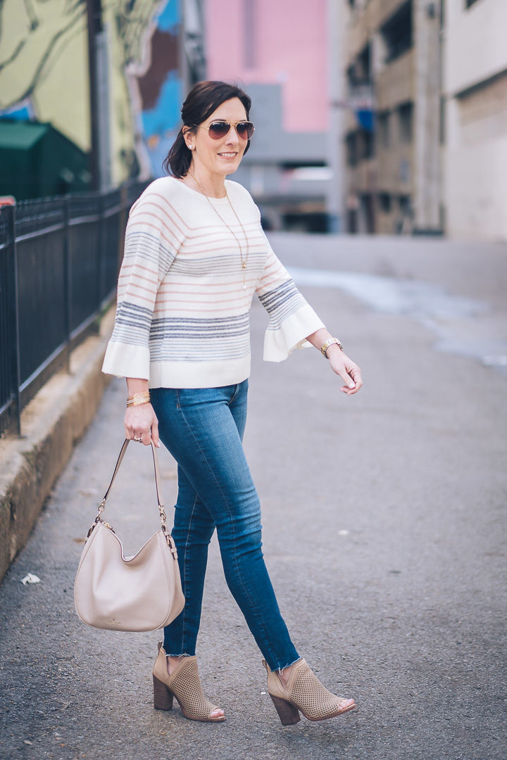 A dressed-up casual spring outfit featuring LOFT mixed stripe bell sleeve sweater with AG raw hem legging ankle jeans and Vince Camuto perforated peep toe booties. Also wearing kate spade new york mylie hobo.