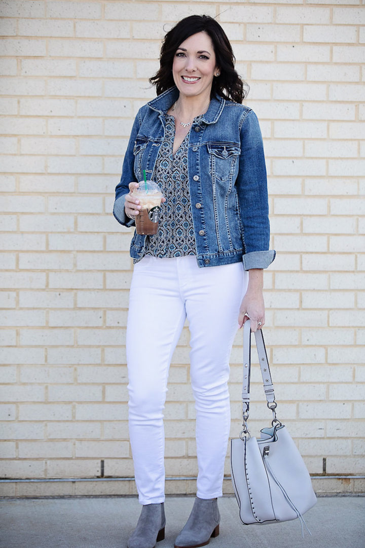Jo-Lynne Shane wearing Two by Vince Camuto denim jacket, LOFT Geo Mixed Media Split Neck Shell, Paige Verdugo white skinny jeans, SARTO by Franco Sarto Seville booties, and R Minkoff Darren shoulder bag 