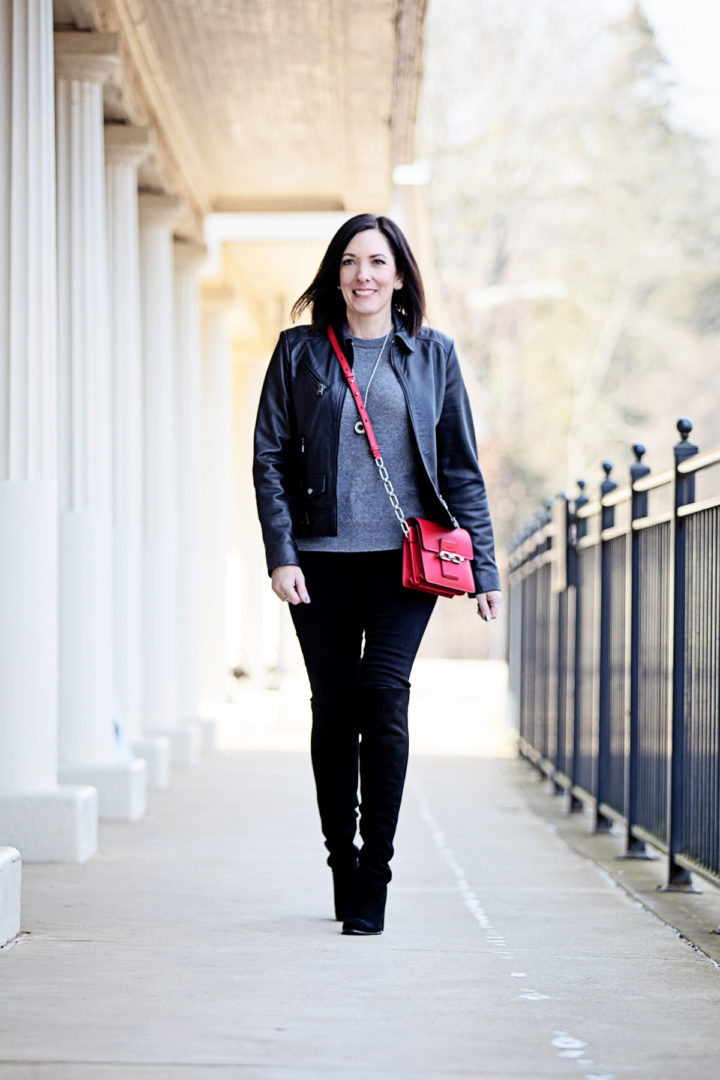 Jo-Lynne Shane styling a winter date night outfit with a leather jacket, suede over the knee boots, black jeans, a grey cashmere sweater, and a red bag... Click through to see how it came together!