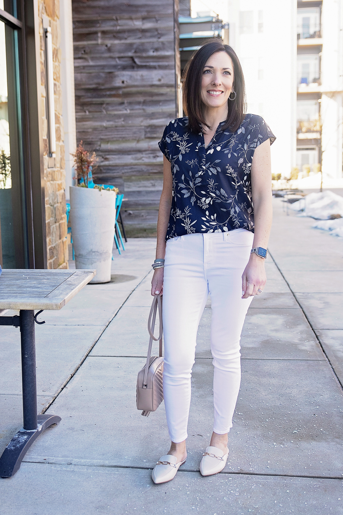 navy floral blouse outfit with white jeans, denim jacket, and loafer mules